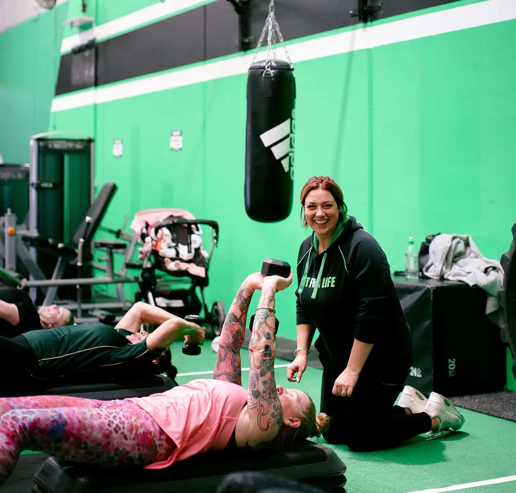 Claire coaching a member through a floor exercise at Fit For Life
